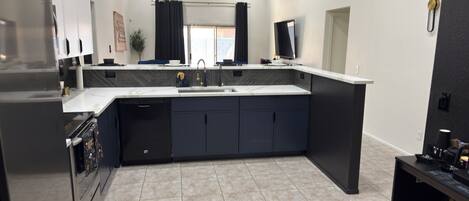 Een moderne keuken met een centraal eiland, inbouwapparatuur en een groot raam.