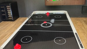 A room with a foosball table, a dartboard, a clock, and a television on the wall. - Beautiful 3-bedroom house with pool & game room in charming Glendale (Glendale)