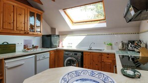 Una cocina con armarios de madera, lavavajillas, lavadora y un tragaluz.