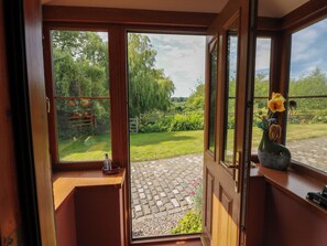 A room with a wooden door leading to a garden with a paved path. - Buchanans Bothy (Perth)