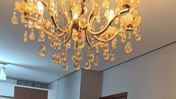 A modern kitchen with a chandelier, a refrigerator, and a dining area with a small table. - Beautiful apartment with ocean views on the Porto Seguro coastline, close to the best beaches. (Porto Seguro)