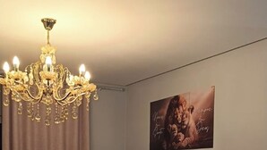 A living room with a dark brown sofa, a round coffee table, a chandelier, and a framed picture on the wall. - Beautiful apartment with ocean views on the Porto Seguro coastline, close to the best beaches. (Porto Seguro)