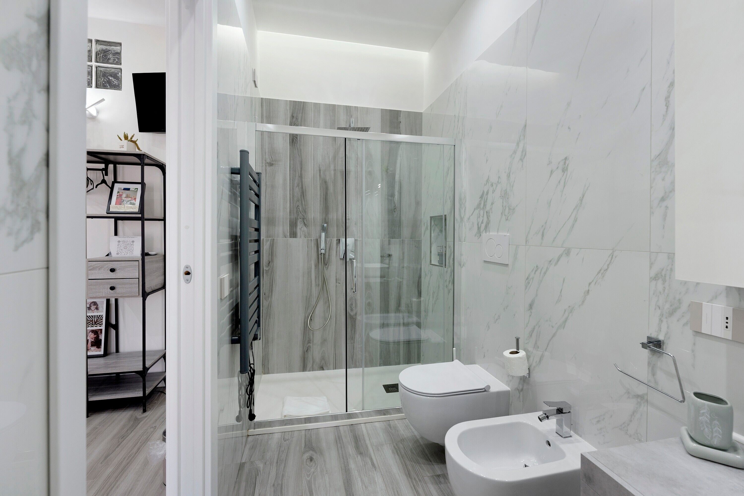 A modern bathroom with a glass-enclosed shower, a white toilet, and a bidet.