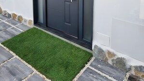 Une porte moderne, dotée d’une poignée et d’un trou de serrure, est encastrée dans un mur blanc, au-dessus duquel on peut voir une petite plaque.