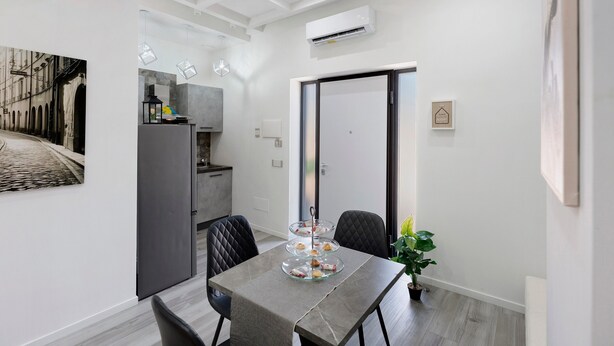 Une cuisine moderne dotée d’un four encastré, un coin repas avec une table et des chaises, et une porte coulissante donnant sur une autre pièce.
