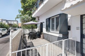 A balcony with outdoor furniture, a car parked on the street, and a building with a window and shutters. - Secretum Pompeii Studio - Deluxe Triple (Pompei)