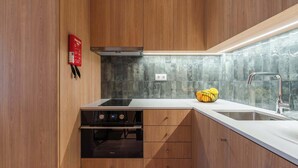 Eine moderne Küche mit Holzausbau, inklusive Einbauherd, Spüle und Spritzschutz.