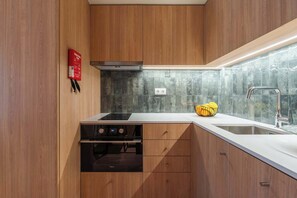 A modern kitchen with wooden cabinets, a built-in stove, a sink, and a backsplash. - 3 Comfy Houses by HostWise (Porto)