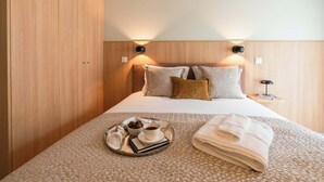 Ein Hotelzimmer mit einem Bett, einem Tablett mit Frühstücksgegenständen und einem ordentlich gefalteten Handtuch.