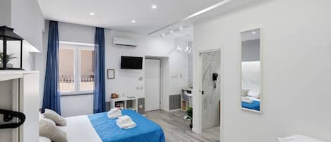 A modern hotel room with a bed, a desk, and a bathroom mirror.