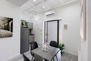 A modern kitchen with a built-in oven, a dining area with a table and chairs, and a sliding door leading to another room.