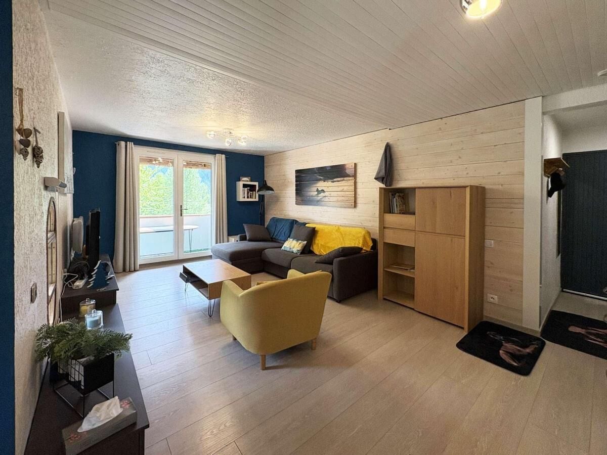 A modern living room with a sofa, armchair, and a wooden cabinet.