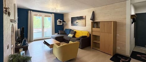 A modern living room with a sofa, armchair, and a wooden cabinet.