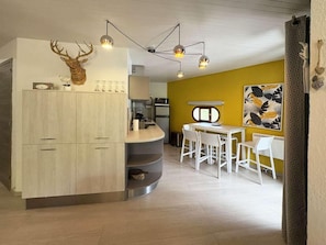 A modern kitchen with a unique deer head decoration, a dining area with white chairs, and a yellow accent wall. - 150m from ski slopes, 6th floor, balcony, 57m², Les Orres (Les Orres)