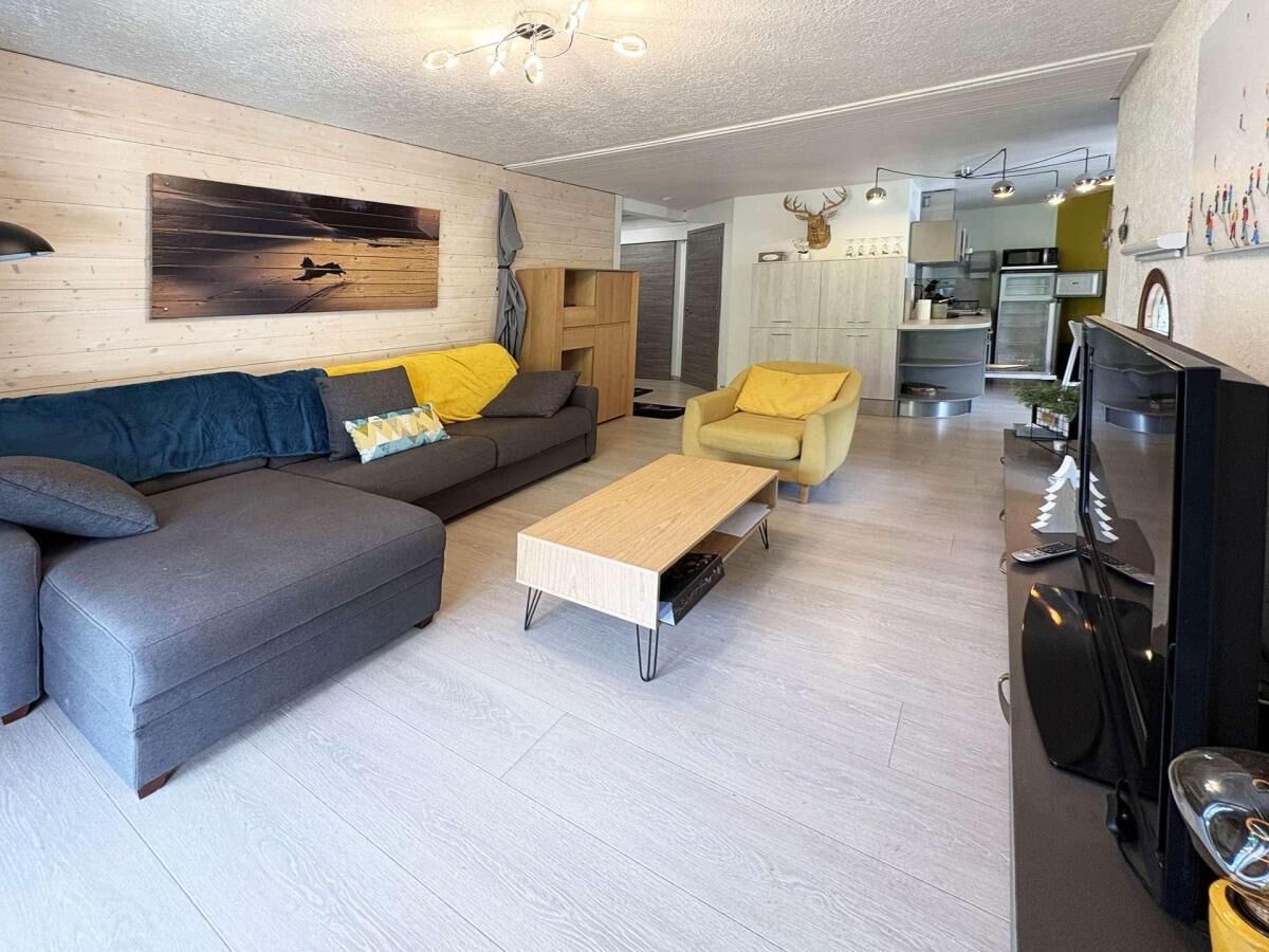 Ein modernes Wohnzimmer mit einem grauen Sofa, gelben Sessel und einem Couchtisch.