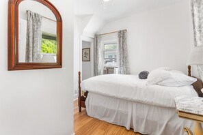 Un dormitorio con una cama grande, cabecera de madera, mesita de noche y un espejo.