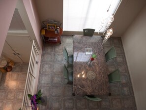 A dining area with a marble table, green chairs, a chandelier, and a window with blinds. - Elegant, Stylish & Spacious Retreat / 3BD / 2.5 BA (Los Angeles)