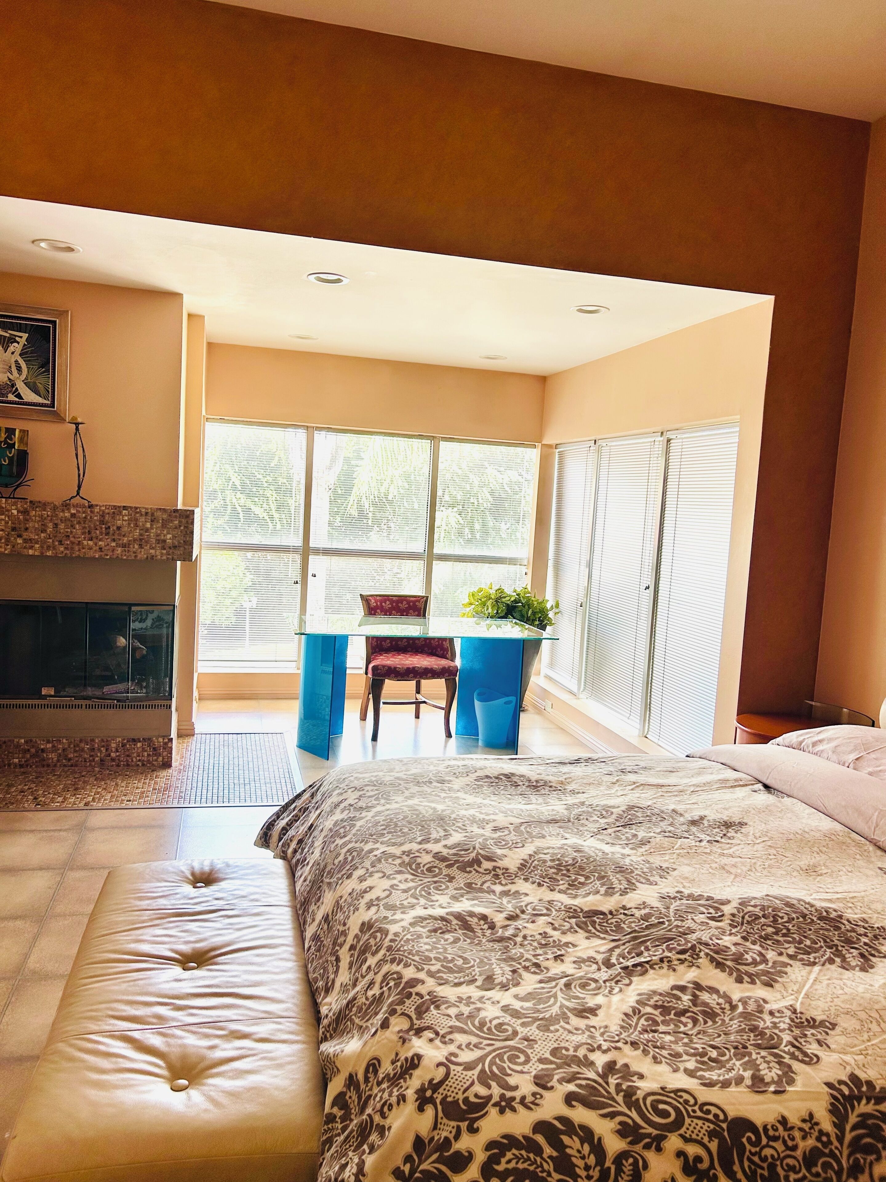 Un dormitorio con una cama grande, una zona de estar con una silla, una mesita y una chimenea.