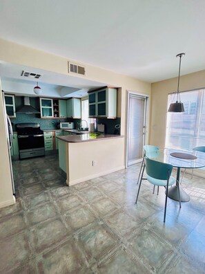 A kitchen with a dining area, a microwave, a stove, and a refrigerator. - Elegant, Stylish & Spacious Retreat / 3BD / 2.5 BA (Los Angeles)