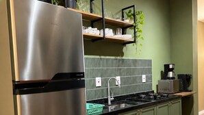 A kitchen with a stainless steel refrigerator, a gas stove, and green cabinets. - Zoe  (Foz do Iguaçu)