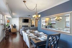 A dining area with a large mirror, a chandelier, and a television mounted on the wall. - Spacious Austin Retreat 3BR Pool Views (Austin)