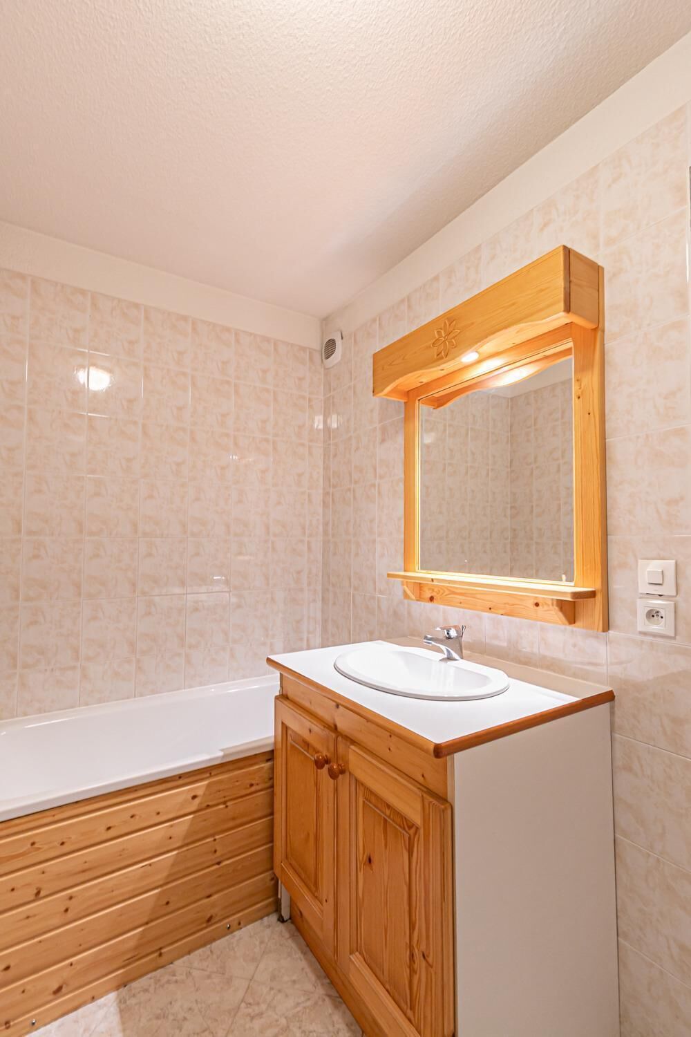 A bathroom with a wooden vanity, a white sink, and a large mirror.