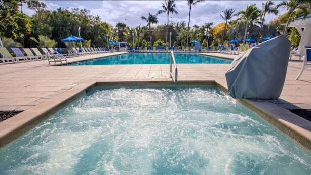 Une piscine agrémentée d’une fontaine, entourée de chaises longues et de parasols.