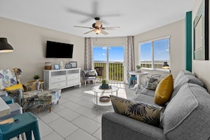 A living room with a ceiling fan, a flat-screen TV, a sofa, a coffee table, and a balcony with a view. - Exceptional OceanView 2/2 heated Pool Beach Marina (Tavernier)