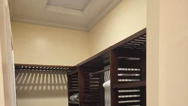 A walk-in closet with multiple shelves and drawers, a hanging rod, and a door with a striped pattern. - Serene Hauula Retreat with Ocean Views (Hauula)