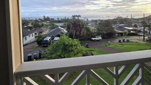 A view from a balcony with a railing, overlooking a residential area with houses and greenery. - Serene Hauula Retreat with Ocean Views (Hauula)