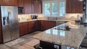 A modern kitchen with granite countertops, stainless steel appliances, and wooden cabinets. - Serene Hauula Retreat with Ocean Views (Hauula)