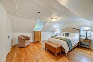 A bedroom with a wooden floor, a bed with a headboard, a bench, a dresser, and a chair. - Cozy Grants Pass Home Near Rogue River Access (Grants Pass)