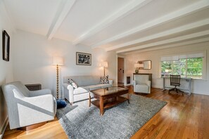 Un salon comprenant un canapé, des fauteuils, une table basse et un bureau avec une chaise.