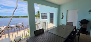 Ein Balkon mit Seeblick, einem Tisch, Stühlen, einem Grill und einer Tür.
