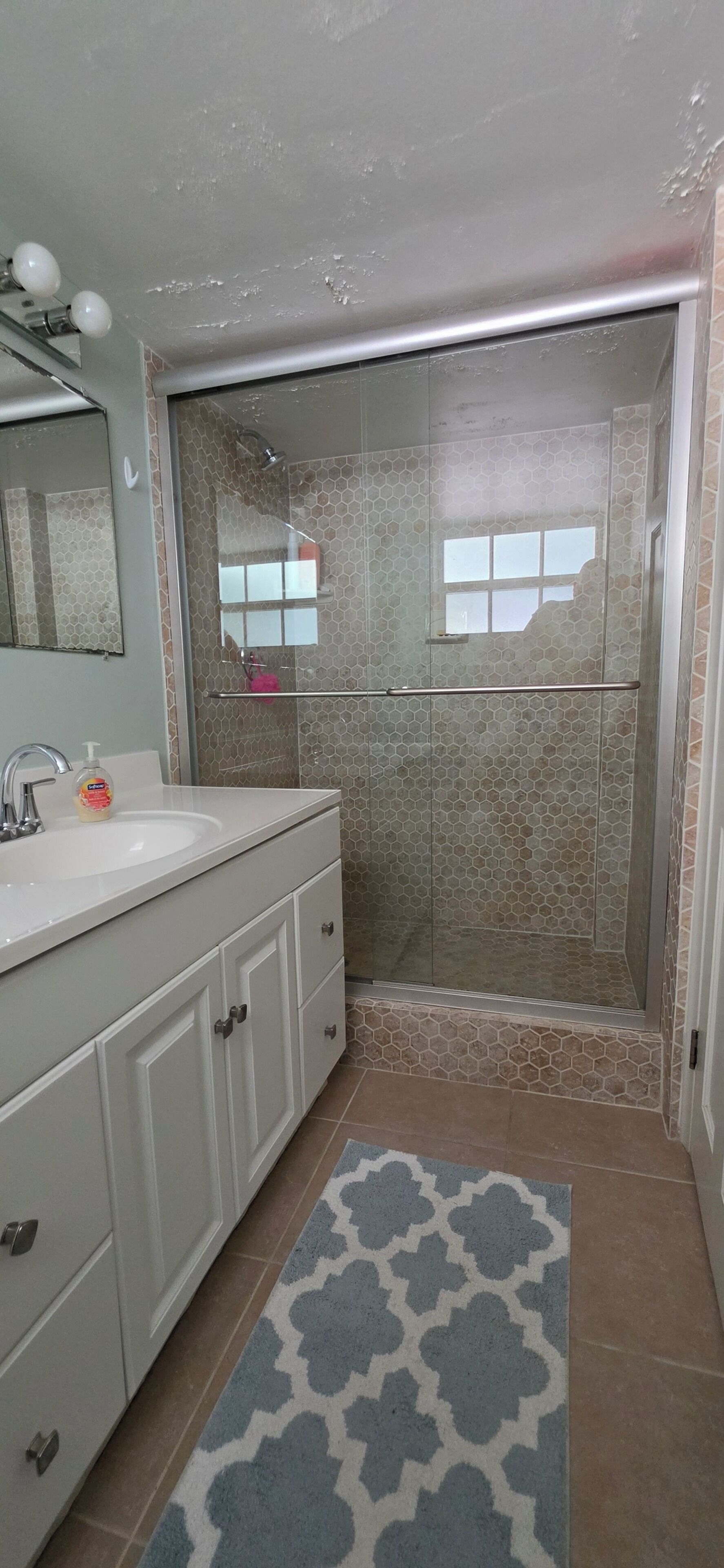 A bathroom with a shower, a sink, and a mirror.