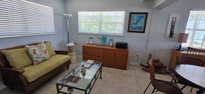 A living room with a sofa, coffee table, side table, and a dining area with chairs and a table. - Islamorada Gem / 5BR Oceanfront Home w/ Stunning Ocean Views (Tavernier)