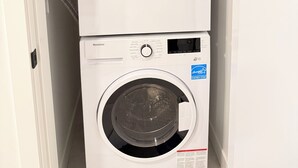 A wall-mounted, stacked washer and dryer unit with a control panel and a digital display. - Modern Condo Steps From SkyTrain-Walkable Location + Amazing Building Amenities (Surrey)