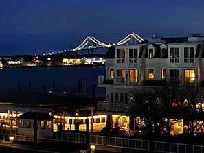 Een pand aan het water met een groot gebouw, meerdere ramen en een balkon, met uitzicht op water en een brug.