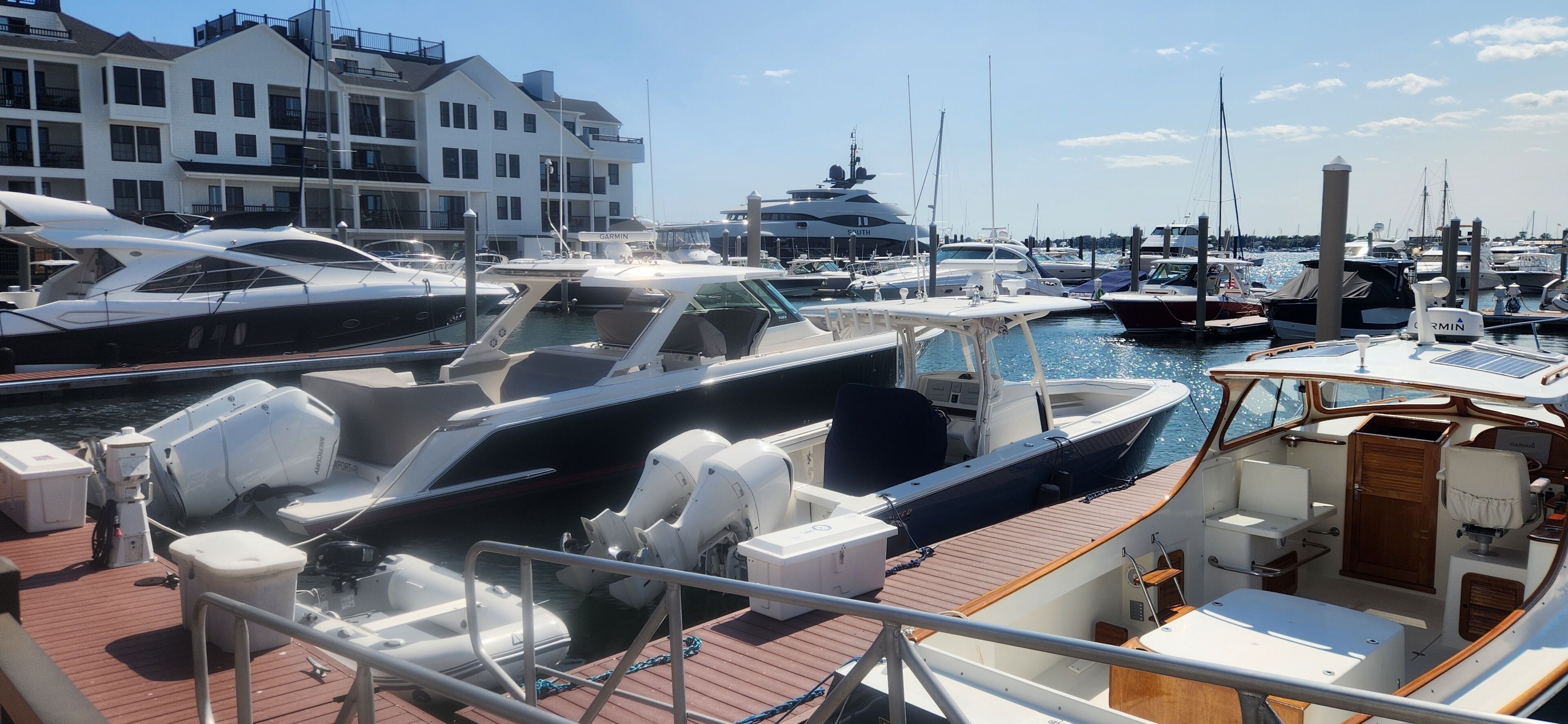 A marina with various boats docked, a building with balconies, and a clear sky.