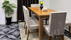 Un coin repas avec une table en bois, quatre chaises, un vase rempli de fleurs jaunes et une plante en pot.