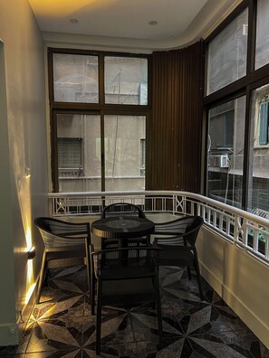 Ein Eckbalkon mit rundem Tisch und vier Stühlen, großen Fenstern und einem gemusterten Boden.