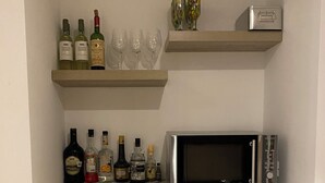 Keittiössä on mikroaaltouuni, hyllyillä viinipulloja ja laseja.