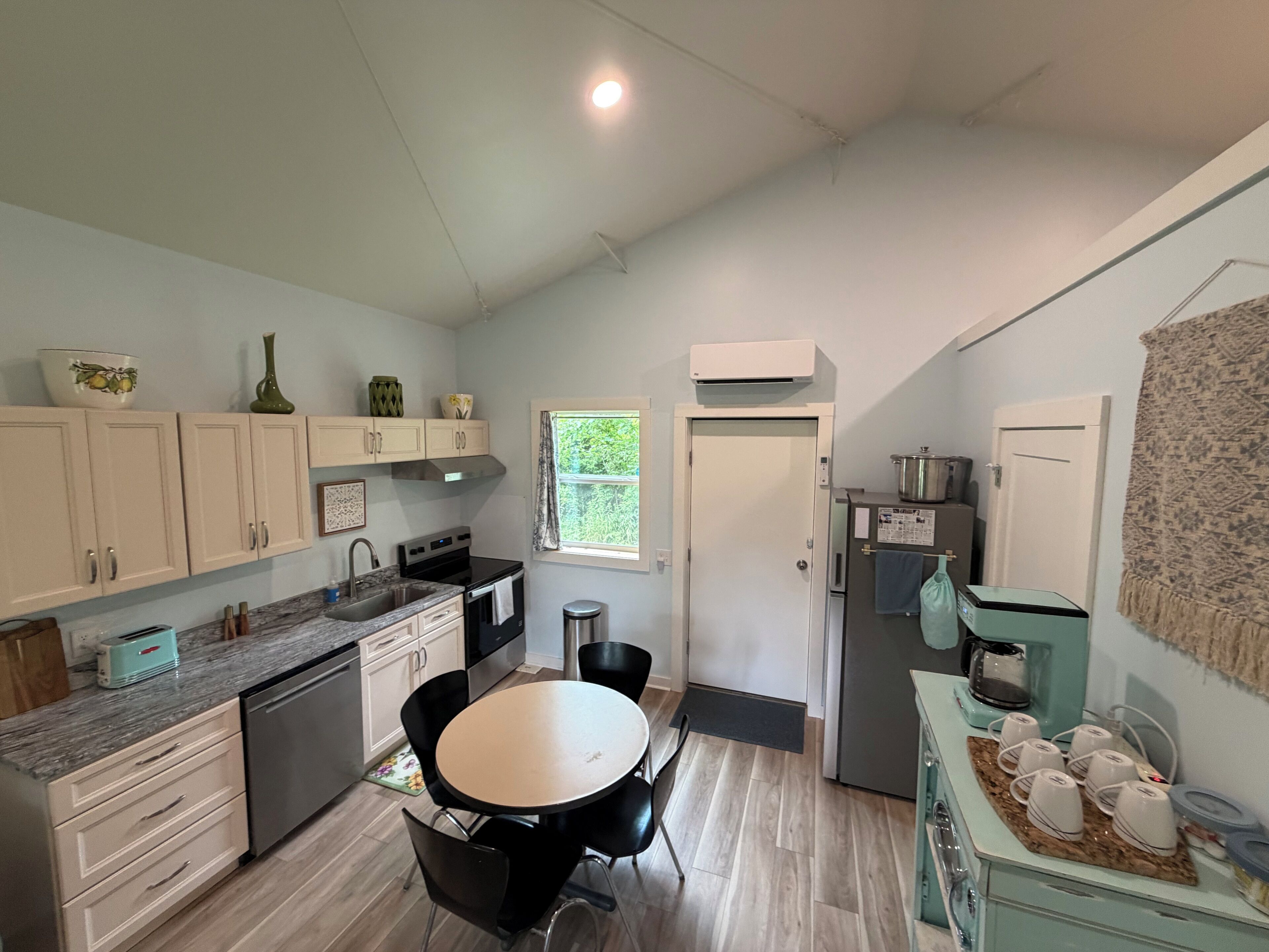 A modern kitchen with a dining area, featuring a stove, sink, and a small table with chairs.