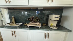 Cocina con armarios blancos, cafetera y diversos utensilios de cocina.