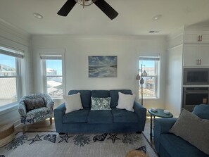 A living room with a blue sofa, a patterned armchair, a starfish rug, and a painting of a seascape. - New Luxury Beach Retreat  4 Bedrooms 3 King beds  Elevator  Steps to the Beach (Carolina Beach)
