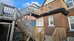 Una escalera de madera que conduce a un balcón, con un edificio de ladrillo al fondo.