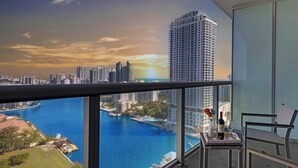 A balcony with a city view, a table with a bottle and glass, and a chair. - 28th Floor Studio w Marina View & Pool (Hallandale Beach)
