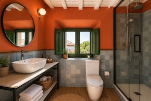 A bathroom with a large oval sink, a toilet, and a shower area.