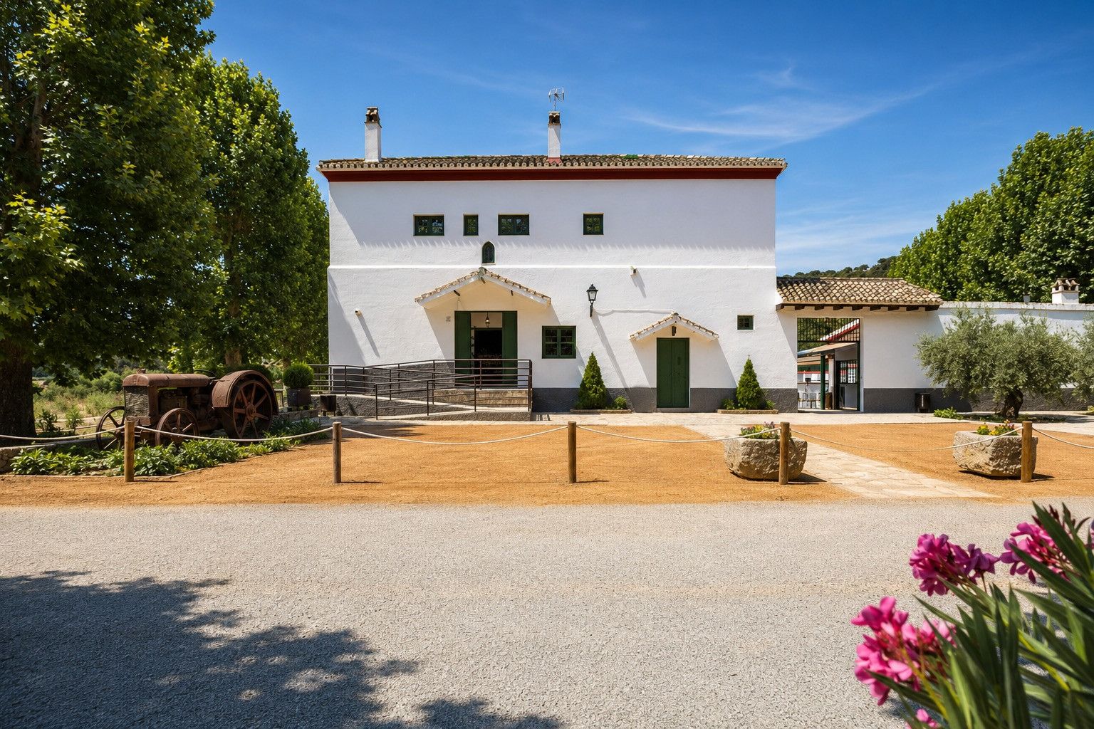 Un bâtiment blanc avec un toit en tuiles, une porte verte et un petit porche.