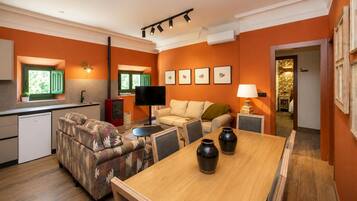 Un espacio habitable compacto con kitchenette, sofá, televisión y mesa de comedor.